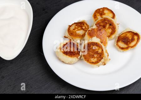 Hausgemachte kleine Käsekuchen Pfannkuchen aus Hüttenkäse Pfannkuchen mit Sauerrahm Stockfoto