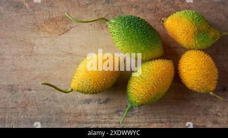 Dorn oder Stachelkürbis verstreut auf hölzernem Hintergrund, Teasle Kürbis oder bunt Balsam Birne kleine dunkelgrüne und gelbe ovale Früchte Stockfoto