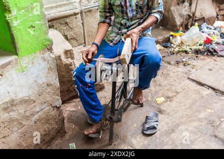 Indien, Uttar Pradesh, Varanasi, Bangali Tola. Mann schärft Messer mit einem selbstgemachten, fahrradbetriebenen Schleifstein. Stockfoto