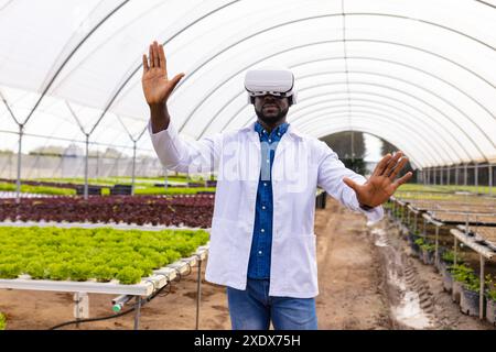 Mit dem VR-Headset erforscht Afroamerikaner Technologie im Hydrokultur-Gewächshaus Stockfoto