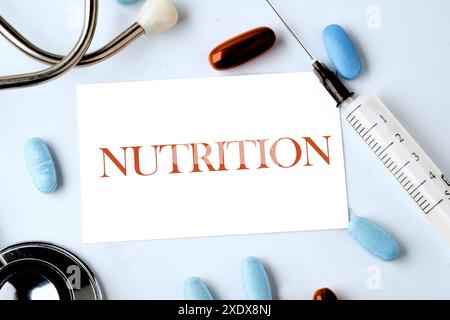 NÄHRWERTWORT auf einer Visitenkarte auf blauem Hintergrund mit einem Stethoskop, Pillen und einer Spritze in der Zusammensetzung Stockfoto