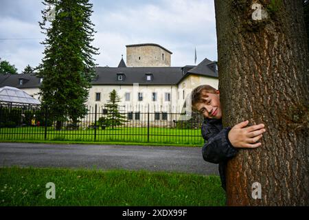 Der Junge umarmt einen Baum im Park einer mittelalterlichen Burg. Stockfoto