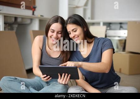 Glückliche Mitbewohner, die Online-Informationen zum Tablet-Reforming-House abrufen Stockfoto