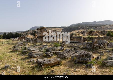 An einem sonnigen Tag in der Nähe der Stadt Pamukkale bietet sich ein fantastischer Blick auf die zerbröckelnden historischen Gebäude in der alten Ruinenstadt Hierapolis in Türkiye. Stockfoto