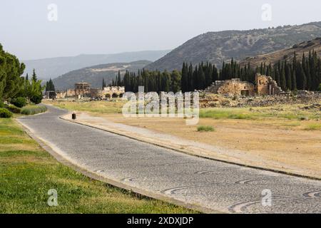 An einem sonnigen Tag in der Nähe der Stadt Pamukkale bietet sich ein fantastischer Blick auf die zerbröckelnden historischen Gebäude in der alten Ruinenstadt Hierapolis in Türkiye. Stockfoto