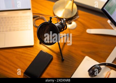 Podcasting-Einrichtung mit Mikrofon, Laptop und Smartphone auf Holztisch, Kopierbereich Stockfoto