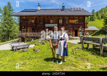 Bettina und Manfred Huber stehen vor der Filzmoosalm im Großartltal, Salzburg, Österreich, die sie seit 2018 führen. Die Hütte, auf 1.710 Metern, stammt aus dem Jahr 1954, nachdem eine Lawine das vorherige Gebäude der Familie Promegg im Jahr 1950 zerstörte. Solarmodule auf dem Dach versorgen den Betrieb nun mit Strom. Stockfoto