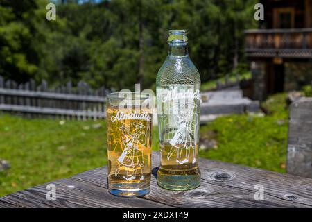Ein Glas und eine Flasche Almdudler stehen auf einem Tisch vor der Filzmoosalm im Großartltal, Salzburg, Österreich. Die 1957 eingeführte Kräuterlimonade ist eine der bekanntesten Softgetränke Österreichs. Stockfoto