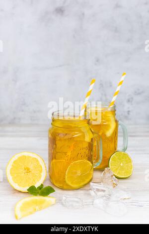 Traditioneller Eistee mit Zitrone, Minze und Eis in hohen Gläsern. Weißer Holzhintergrund. Ein erfrischendes Getränk im Sommer. Stockfoto
