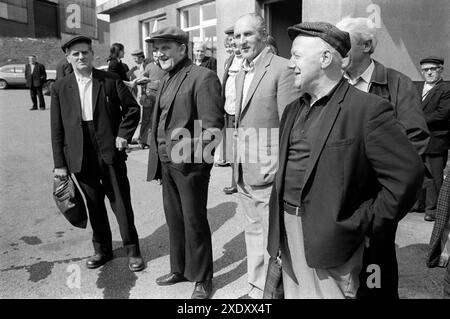 Coal Miners 1970er Jahre Yorkshire UK. Vor der Zeche warten vier Bergleute auf den Transport, um sie nach Hause zu bringen. Das Gebäude dahinter ist das Colliery Engineers and Records Office. Im Hintergrund befindet sich die Ferrymoor Riddings Drift Mine. South Kirkby, Yorkshire England 1979. HOMER SYKES AUS DEN 1970ER JAHREN Stockfoto