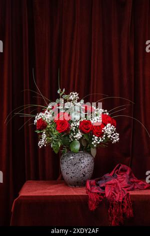 Ein riesiger Strauß roter Rosen mit weißen Blumen auf einem dunkelbraunen Stoff. . Der Boden des Straußes ist auf dem Foto eingerahmt. Postkarte, Glückwunsch Stockfoto