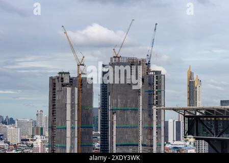 Zeitraffer-Blick auf große Baukräne, die auf Hochhäusern in Bangkok, Thailand, mit sich bewegenden Wolken und Hochhäusern in BA arbeiten Stockfoto