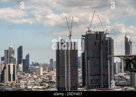 Zeitraffer-Blick auf große Baukräne, die auf Hochhäusern in Bangkok, Thailand, mit sich bewegenden Wolken und Hochhäusern in BA arbeiten Stockfoto