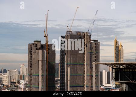 Zeitraffer-Blick auf große Baukräne, die auf Hochhäusern in Bangkok, Thailand, mit sich bewegenden Wolken und Hochhäusern in BA arbeiten Stockfoto