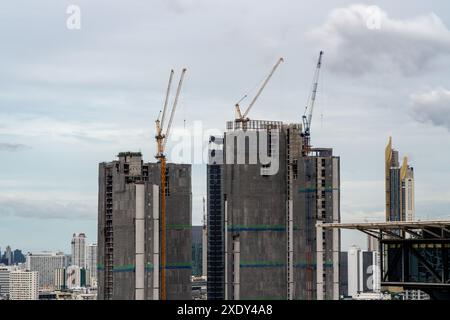 Zeitraffer-Blick auf große Baukräne, die auf Hochhäusern in Bangkok, Thailand, mit sich bewegenden Wolken und Hochhäusern in BA arbeiten Stockfoto