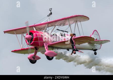 46 Aviation Boeing Stearman Doppeldecker Wing-Walking-Ausstellung auf der Sywell Airshow 2024 in Northamptonshire, Großbritannien. Danielle Del Buono hängt kopfüber Stockfoto