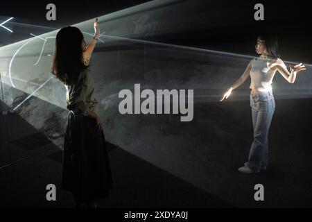 London, Großbritannien. 25. Juni 2024. Besucher erleben ein immersives Kunstwerk bei der Vorschau von „Solid Light“, einer Ausstellung mit Werken von Anthony McCall im Tate Modern. Lichtstrahlen werden durch einen dünnen Nebel projiziert, wodurch große dreidimensionale Formen im Raum entstehen, und ihre Formen können von Besuchern beeinflusst werden, die sich durch sie bewegen. Die Ausstellung findet vom 27. Juni 2024 bis zum 27. April 2025 statt. Quelle: Stephen Chung / Alamy Live News Stockfoto