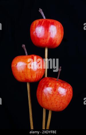 Rote, handgefertigte Kunststoffäpfel für die Dekoration von Tannenbäumen isoliert auf schwarzem Makro Stockfoto