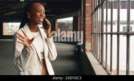 Selbstbewusste Geschäftsfrau, die am Telefon in modernen industriellen Büroflächen kommuniziert Stockfoto