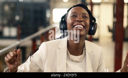 Fröhliche Geschäftsfrau, die Musik im modernen Industriebüro hört Stockfoto