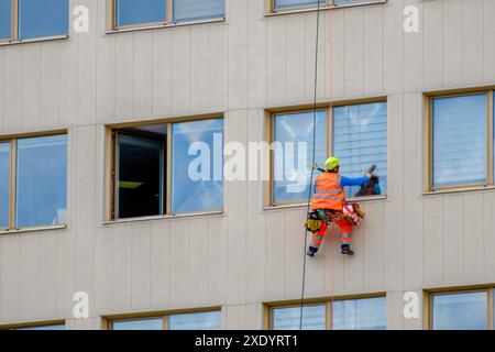 Minsk, Weißrussland - 11. April 2022: Industriekletterer wäscht Fenster an der Fassade eines Gebäudes im Geschäftsviertel Stockfoto