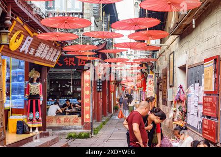 Fenghuang, China - 23. September 2017: Herrlicher Blick auf die gemütliche, enge Straße, die mit traditionellen orientalischen chinesischen roten Regenschirmen dekoriert ist. Stockfoto