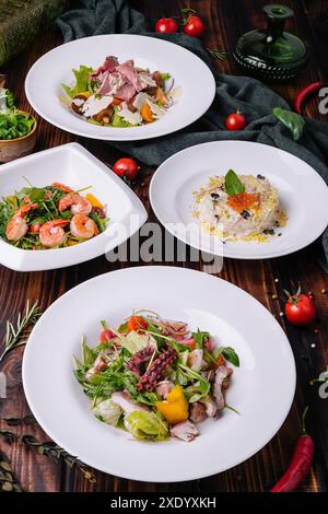 Verschiedene Salate in weißen Tellern auf einem Holztisch Stockfoto