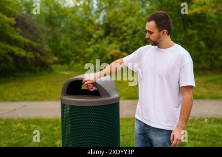 Mann, der mit Müll läuft. Plastikbeutel mit der Hand gegen Mülltonnen auf der Straße tragen. Stockfoto