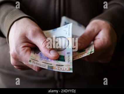 Weißer Mann, der ukrainische Geldscheine aus der Nähe gibt Stockfoto
