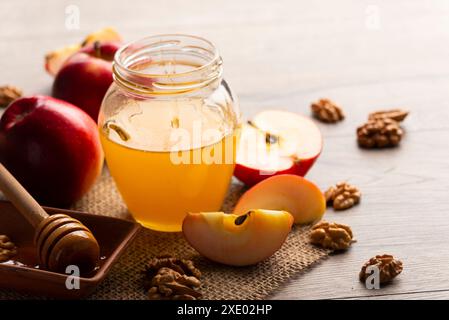 Einmachglas mit Honig Honig Dipper rote Äpfel und Walnüsse auf Küchentisch Stockfoto