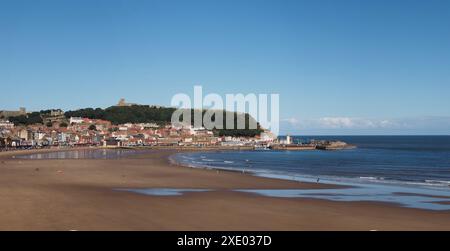 Breiter Panoramablick auf die Stadt Scarborough vom Strand der Südbucht mit Grand Hotel, Schloss und Leuchtturm und einem sonnigen Licht Stockfoto