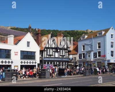 Touristen, die an Cafés und dem newcastle Packet Pub am Sandstrand in scarborough bei Sommersonne vorbeilaufen Stockfoto