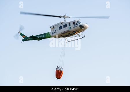 Feuerwehrhelikopter während des Fluges, der Wasserbeutel auf Flammen abwirft Stockfoto