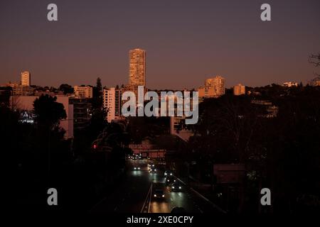 Skyline von Sydney in der Abenddämmerung mit Blick auf die New South Head Road, Kings Cross nach Edgecliff, einem Strom von Scheinwerfern und Wohngebäuden, die leuchten Stockfoto