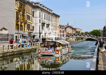 Ein Ausflugsboot voller Menschen auf der Naviglio Grande Wasserstraße mit der Ponte Alda Merini im Frühjahr, Mailand, Lombardei, Italien Stockfoto