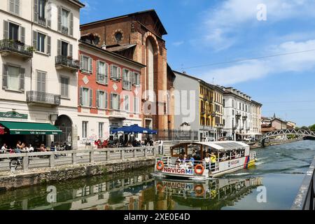 Tour Boot voller Menschen auf dem Naviglio Grande Wasserweg vor der Kirche Santa Maria delle Grazie (1909) im Frühling, Mailand, Lombardei, Italien Stockfoto