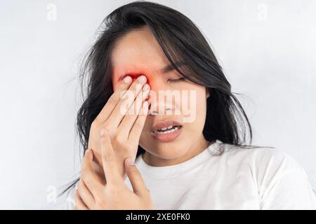 Eine Frau mit roten Augen und schwarzem Gesicht. Sie hält ihr Gesicht und reibt sich die Augen. Schmerzen. Eine müde und gestresste Frau leidet unter starken Augenschmerzen. Stockfoto