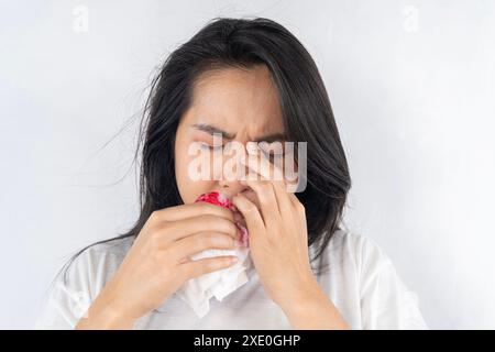 Asiatische Frauen in Satin Nachtwäsche mit Nasenbluten oder Nasenbluten gegen grauer Hintergrund, Nasenhöhle, den asiatischen Menschen weh tut, ihre Nase Stockfoto