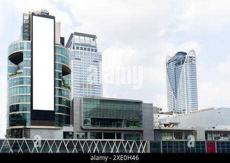 Große weiße Plakatwand an der Seite eines Gebäudes in Bangkok, Thailand. Reklametafeln befinden sich in einem geschäftigen Geschäftsviertel und sind von anderen hohen B umgeben Stockfoto