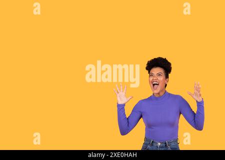 Junge Frau, die aufgeregt vor gelbem Hintergrund schreit, Kopierraum Stockfoto