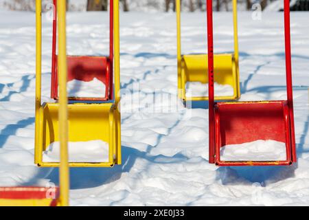 Kinderschaukeln im Winter. Der Begriff der Leere und der Trostlosigkeit Stockfoto