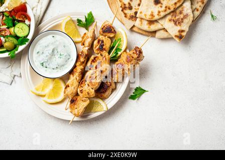 Gegrillte Hähnchenspieße, Kräuter-Joghurt-Sauce und Gemüsesalat. Geröstetes Souvlaki, griechischer Salat, Tzatziki und Pita-Brot auf weißem Hintergrund, Kopie sp Stockfoto