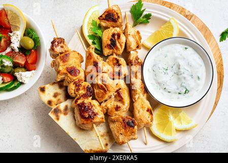 Gegrillte Souvlaki-Spieße, griechischer Salat und Tzatziki-Sauce auf Teller in Nahaufnahme. Mediterranes griechisches Mittagessen mit gebratenem Fleischkebabs, Pita-Brot und Vegetab Stockfoto