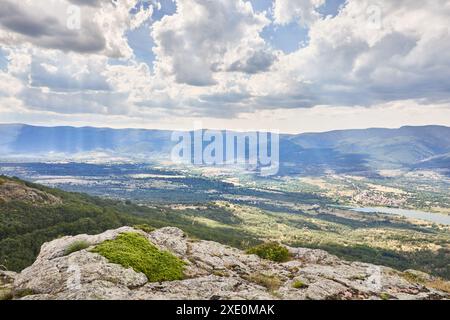 Herrlicher Blick auf das Lozoya-Tal, die Stadt Rascafría und den Pinilla-Stausee von der Spitze des Berges, mit Wolken und Sonnenstrahlen, Stockfoto