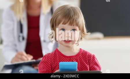 Porträt eines kleinen Mädchens auf dem Hintergrund eines Arztes im weißen Mantel. Kinderuntersuchung und medizinisches Versorgungskonzept Stockfoto