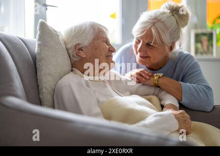 Glückliche Seniorin mit ihrer erwachsenen Tochter zu Hause Stockfoto