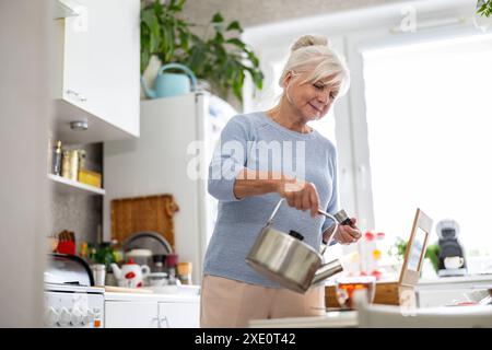 Reife Frau bereitet Tee in ihrer Küche vor Stockfoto