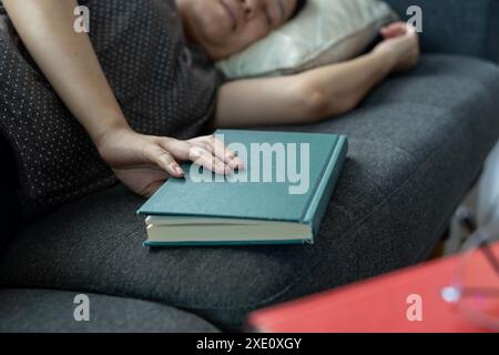 Eine junge Frau schlief beim Lesen eines Buches ein Stockfoto