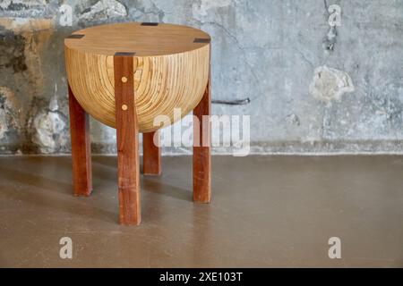 Rustikale niedrige runde Holzbank mit Marmorrückwand im Inneren eines Kellers. Stockfoto