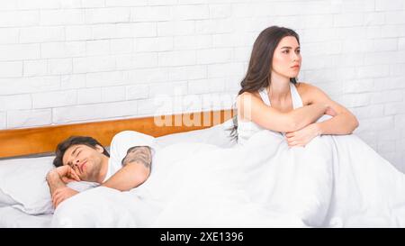 Frau, die im Bett sitzt, während der Mann schläft Stockfoto